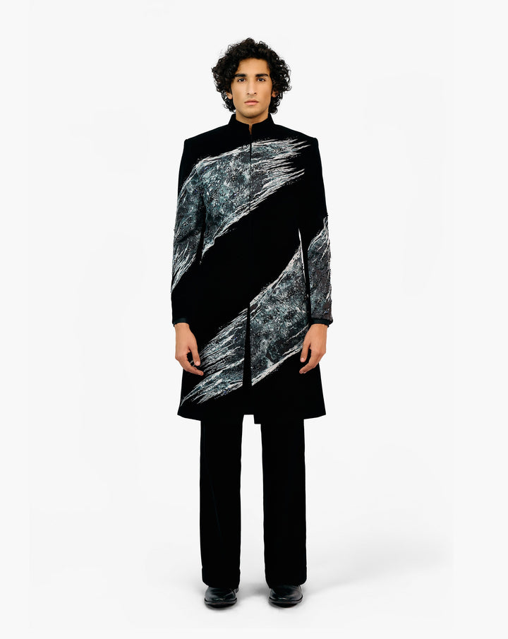 Person wearing a black coat with silver diagonal patterns and black pants by Gaurav Gupta