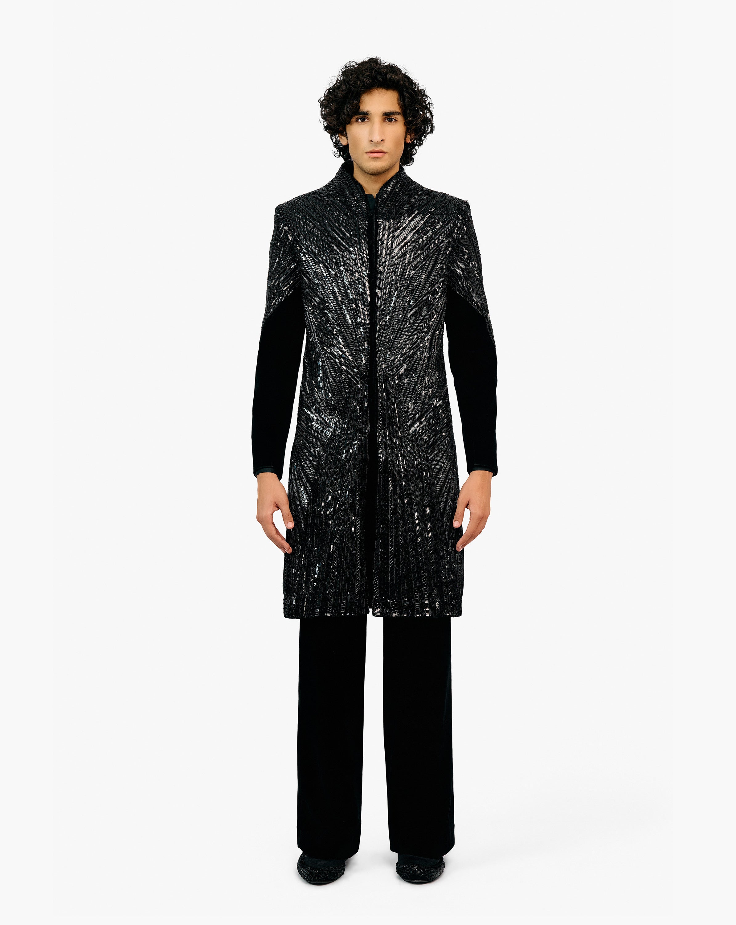 Model wearing black coat with silver patterns with black pant by Gaurav Gupta