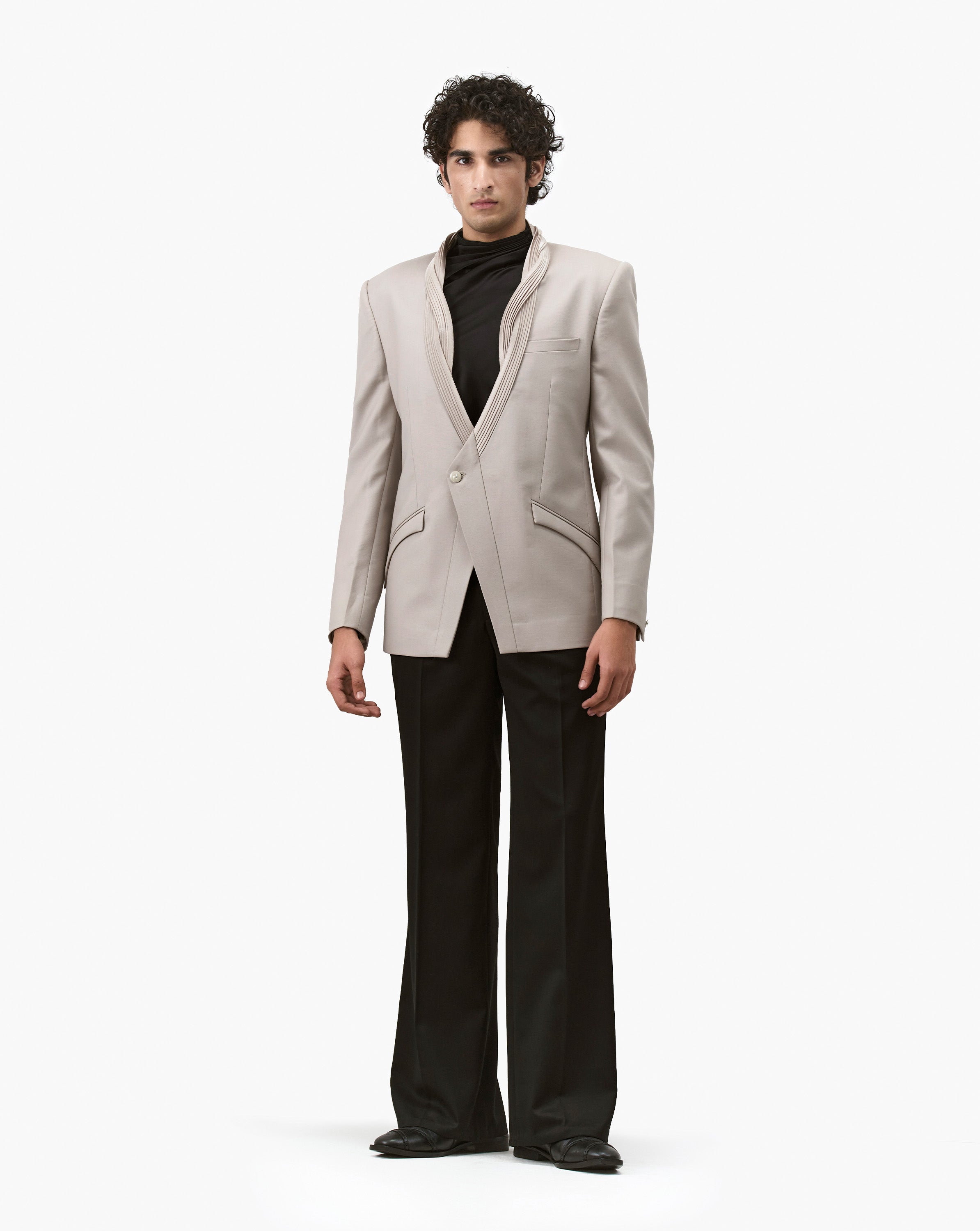 Man wearing a beige embroidered blazer with black flared pants by Gaurav Gupta